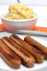 Four large pan grilled frankfurters with mash in the background