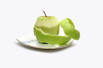 Green apple and its peel on plate on white background