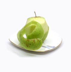 Green apple and its peel on plate on white background