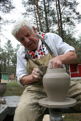 Old potter working with clay on wheel