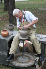 Old potter working with clay on wheel