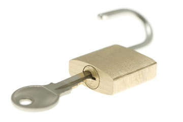 Just-opened brass padlock with key. Isolated