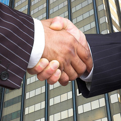 Businessmen in pinstripe suits shake hands.