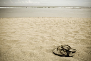 A pair of sandals and sunglasses on a serene beach