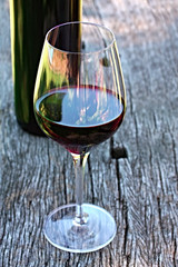 Glass of red wine with bottle behind
