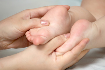 Woman's hands holding a child's foots.