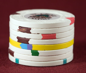 Stack of old clay poker chips on a maroon felt background.