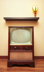 A retro TV sits below a shelf and a tulip lamp.