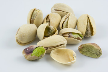dozen of salted and roasted pistachio nuts on white