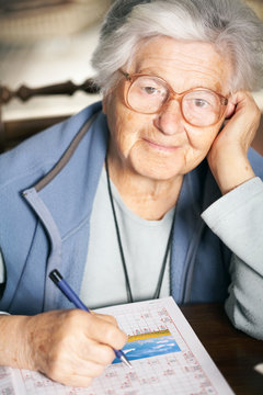Senior woman solving crossword puzzle, portrait