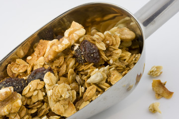 metal scoop full of healthy, organic granola on white background