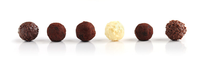 Row of assorted chocolate truffles on white background © Elenathewise