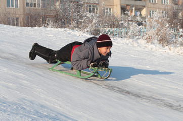 happy asian boy on sledge in bright winter day