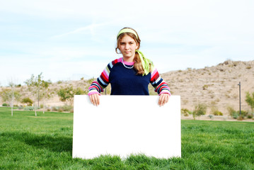 young girl is holding a blank board at outdoor location