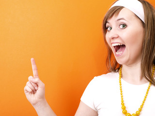 Pointing finger. Smiling girl on the orange background