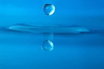 isolated water droplet over blue, with reflection