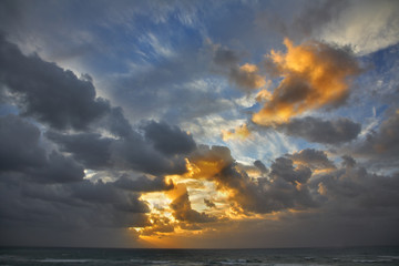 Clouds above the sea the sun shined by beams on a decline