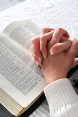 Female hands clasped in prayer ove a Bible © R. Gino Santa Maria