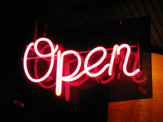 A neon "open" sign glowing red in the window of a restaurant.