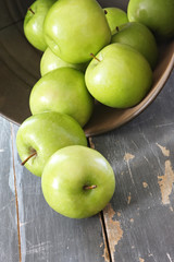 Green Granny Smith apples, spilling from a rusted bucket 