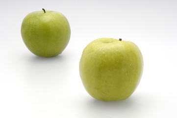 Two fresh green apples lying on a white background