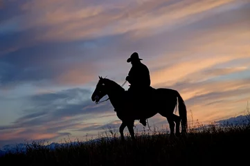 Fotobehang Cowboy on horseback back lit by the dawn sky © outdoorsman