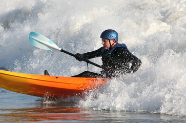 Kayak surfer paddling in rough seas