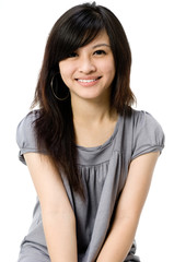 A cute young Asian teenager in grey dress on white background