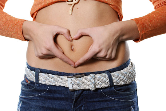 Hands representing heart on a stomach of the girl
