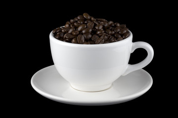 White cup filled with coffee beans on saucer 