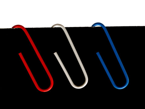Red, white and blue paper clips on black card
