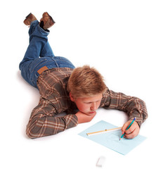 Blond boy drawing a pencil picture lying on the floor