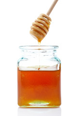 Pouring honey on glass jar, on white background