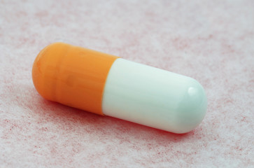 Single medical capsule macro isolated on the pink surface