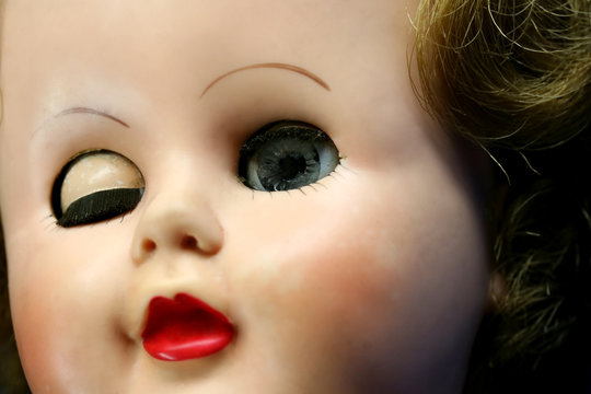 Close up of a doll face with one eye closed