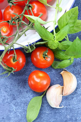 Cherry tomatoes in old enamel bowl, with fresh basil and garlic 