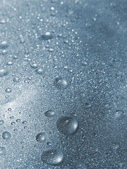 Blue water droplets in a glass surface background
