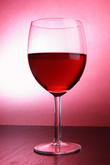 Footed glass of wine over red background