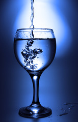 Clear liquid pour into footed glass toned in blue color