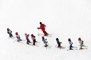 winter scene: kids learning to ski and their instructor