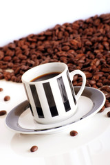 some isolated coffee beans and a cup