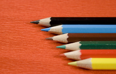 six coloured pencils over red background