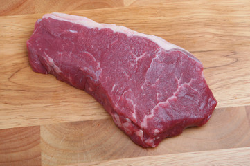 Piece of raw sirloin steak on a wooden chopping board