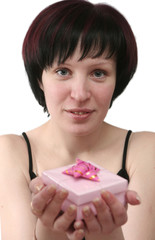 The girl holds in a hand a gift in pink packing