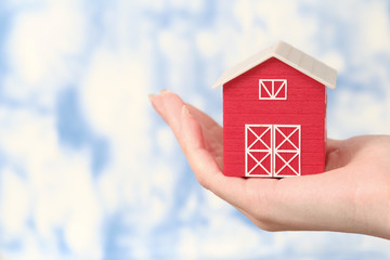  The red house is in a female hand a background of the sky