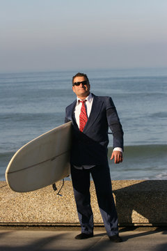 homme en costume avec une planche de surf