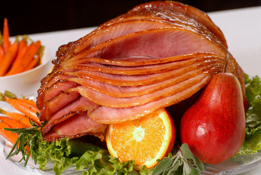 A spiral cut honey glazed Easter ham with fruit and carrots