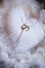 Wedding rings on a white textile heart