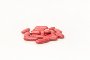 Red vitamin tablets on a white surface