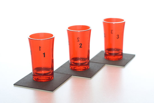 Three red glass numbered glasses on black supports 